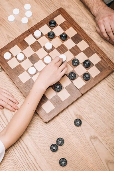 Vista de ángulo alto del hombre y la mujer jugando damas en la mesa - foto de stock