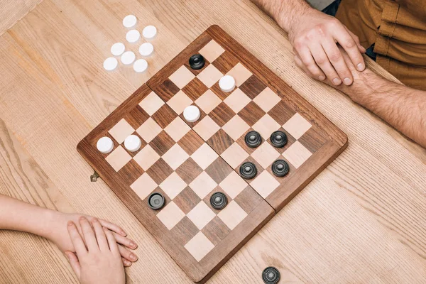 High angle view of man and woman playing checkers at wooden table — Stock Photo