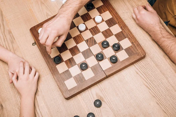 High angle view and man and woman playing checkers on wooden checkerboard — Stock Photo