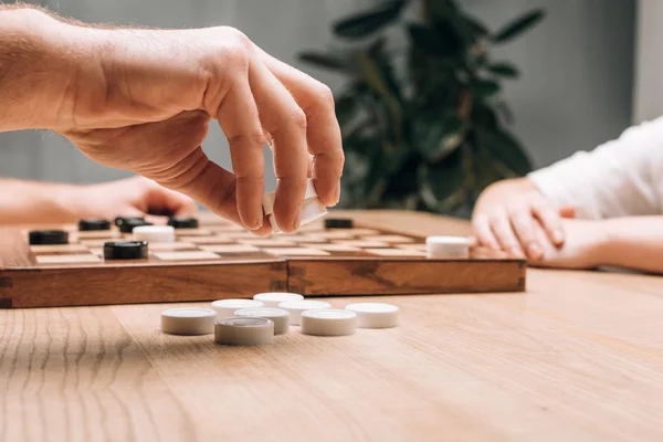 Seitenansicht eines Mannes, der weiße Steine hält, während er mit einer Frau am Tisch spielt — Stockfoto