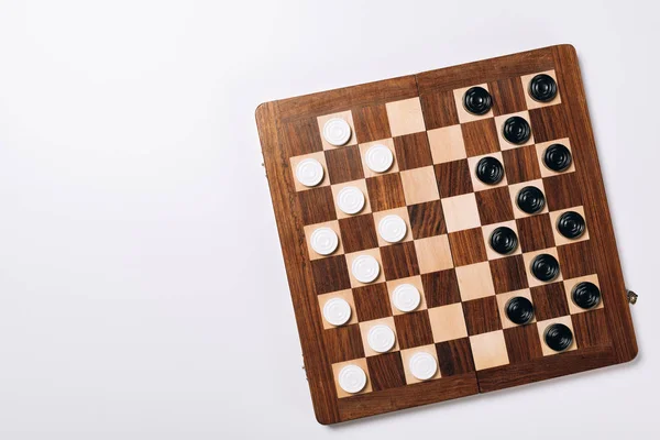 Top view of black and white checkers on wooden chessboard on white background — Stock Photo