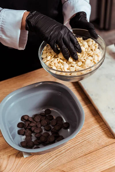 Vista cortada de chocolatier adicionando chips de chocolate branco em tigela — Fotografia de Stock
