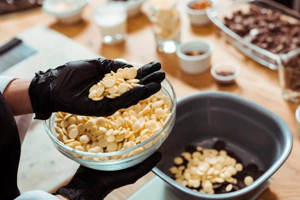 Cropped view of chocolatier holding white chocolate chips in hand — Stock Photo