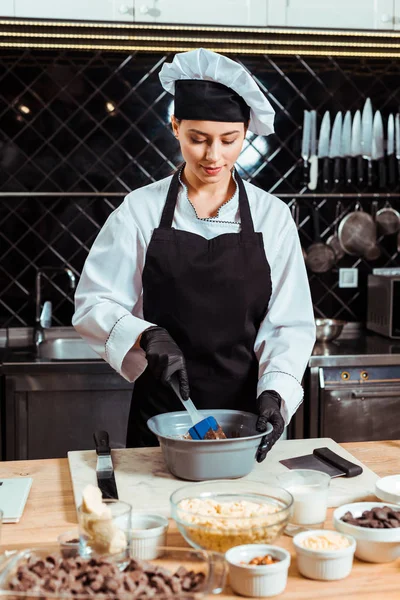 Cioccolatiere allegro con spatola in silicone mentre mescoli il cioccolato in ciotola — Foto stock