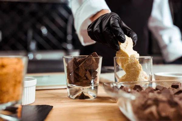 Cropped view of chocolatier taking white chocolate from glass in kitchen — Stock Photo