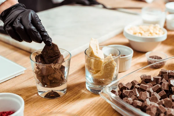 Cropped view of chocolatier taking dark chocolate from glass in kitchen — Stock Photo