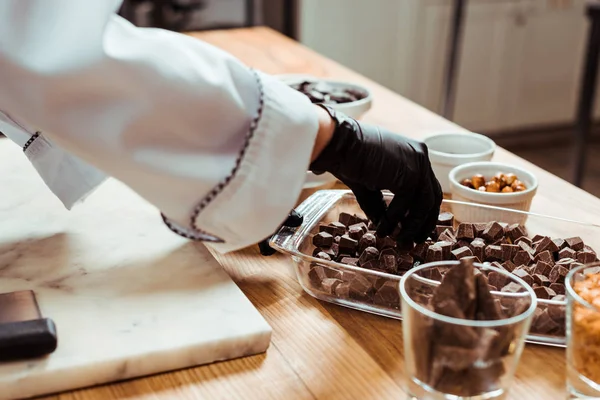 Cropped view of woman taking dark chocolate cubes — Stock Photo