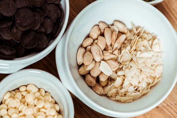 Top view of nutritious nuts near chocolate chips in bowls — Stock Photo