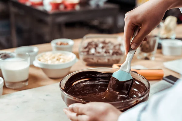 Vista ritagliato di cioccolatiere in possesso di spatola in silicone durante la miscelazione di cioccolato in ciotola — Foto stock