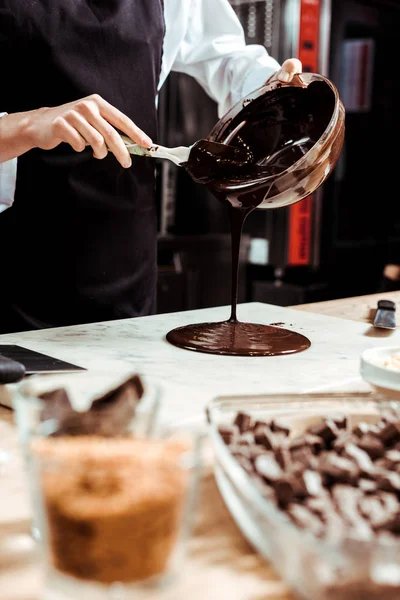 Focalizzazione selettiva del cioccolato fondente versando cioccolato fuso sulla superficie di marmo — Foto stock