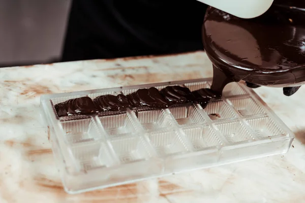 Abgeschnittene Ansicht eines Chocolatiers, der geschmolzene Schokolade in ein Eisfach gießt — Stockfoto