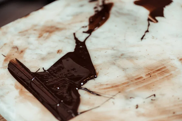 Geschmolzene dunkle und süße Schokolade auf Marmoroberfläche — Stockfoto