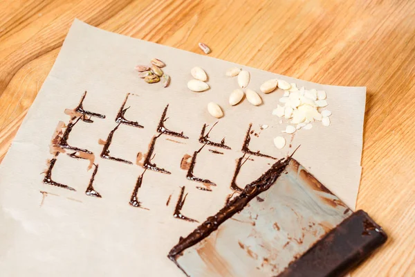 Chocolate stains on baking paper near cake scraper and nuts — Stock Photo
