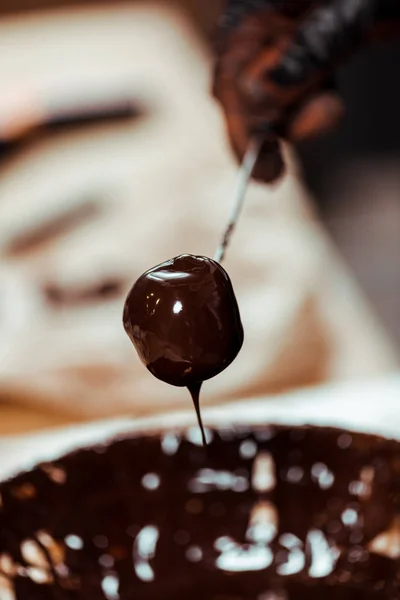 Abgeschnittene Ansicht von Chocolatier Halter Stick mit leckeren Bonbons in der Nähe von geschmolzener Schokolade — Stockfoto