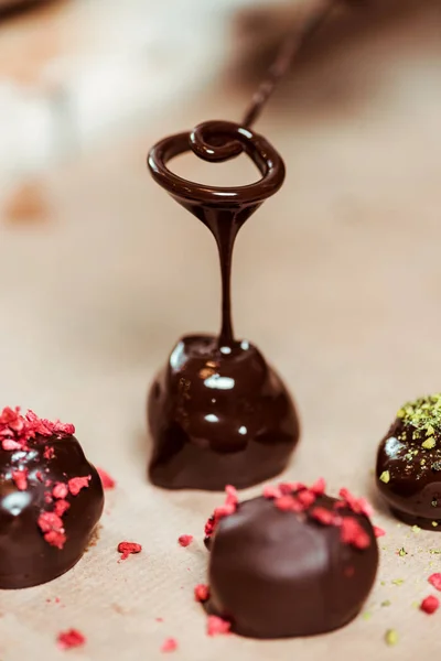 Primer plano de frambuesas secas y polvo de pistacho en bolas de chocolate frescas - foto de stock