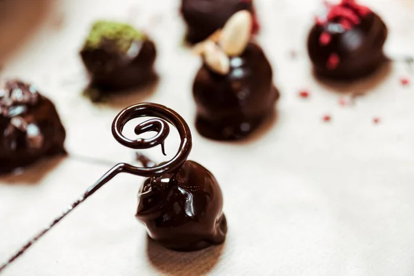 Gros plan de tourbillon près de framboises séchées et de poudre de pistache sur des boules de chocolat fraîches — Photo de stock