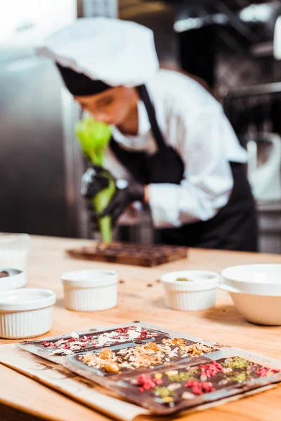 Selektiver Fokus von Schokoriegeln in der Nähe von Chocolatiers, die Teigtaschen halten — Stockfoto