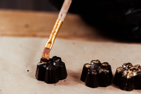 Escova com pó de ouro perto de doces de chocolate preparados — Fotografia de Stock