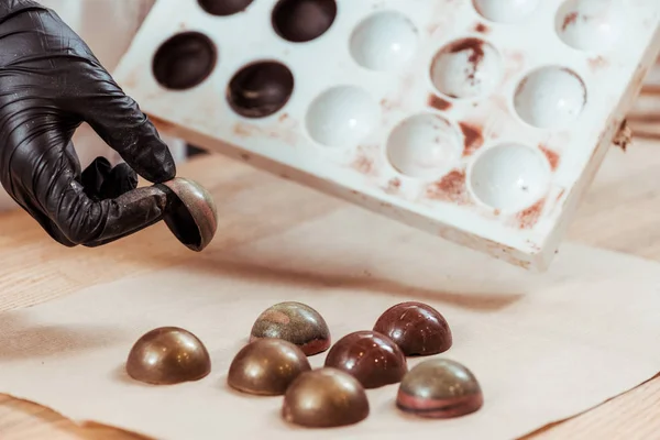 Cropped view of chocolatier holding milk chocolate candy — Stock Photo