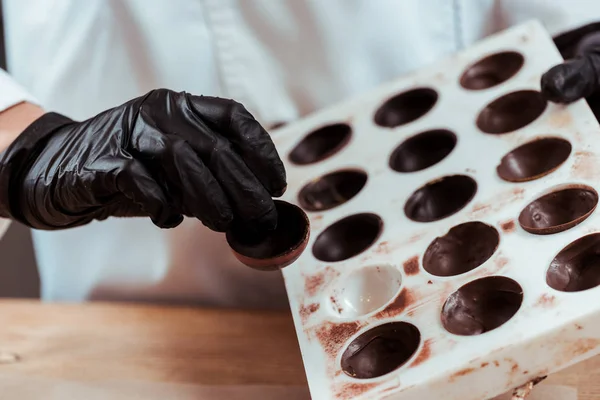 Cropped view of chocolatier holding chocolate candy — Stock Photo