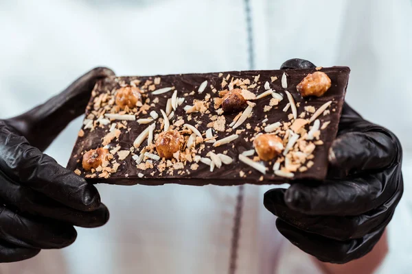 Close up of chocolatier holding tasty chocolate bar with hazelnuts — Stock Photo