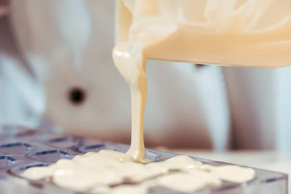 Weiße geschmolzene Schokolade aus Krug in Eisfach gießen — Stockfoto