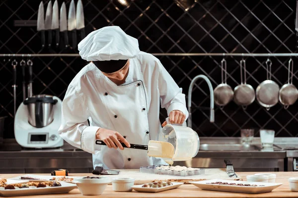 Chocolatier derramando chocolate branco derretido em bandeja de gelo — Fotografia de Stock