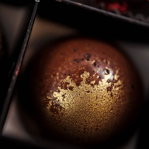 Nahaufnahme von süßer Schokoladenkugel mit goldenem Pulver in Schachtel — Stockfoto