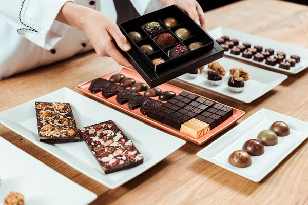 Cropped view of chocolatier holding box with tasty and fresh made chocolate candies — Stock Photo