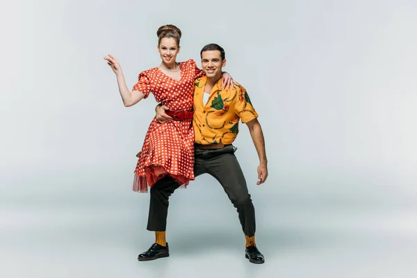 Guapo bailarín holding pareja mientras bailando boogie-woogie en gris fondo - foto de stock