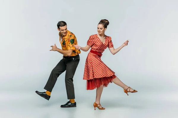 Junge Tänzer halten Händchen, während sie Boogie-Woogie auf grauem Hintergrund tanzen — Stockfoto