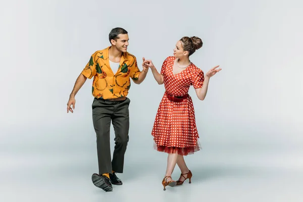 Young dancers looking at each other while dancing boogie-woogie on grey background — Stock Photo