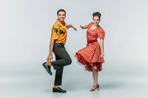 Danseurs élégants regardant la caméra tout en dansant boogie-woogie sur fond gris — Photo de stock