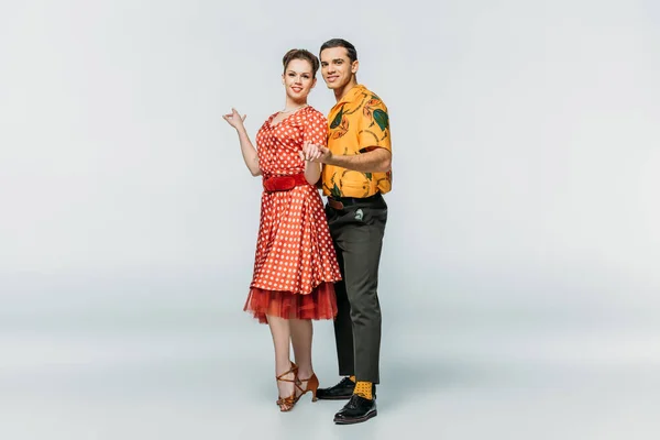 Happy dancers holding hands while dancing boogie-woogie on grey background — Stock Photo