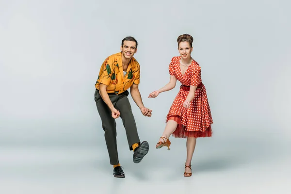 Danseurs joyeux regardant la caméra tout en dansant boogie-woogie sur fond gris — Photo de stock