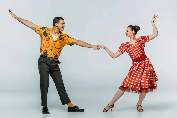 Elegante Tänzer halten Händchen, während sie Boogie-Woogie auf grauem Hintergrund tanzen — Stockfoto