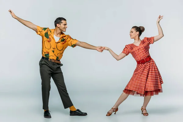 Elegant dancers holding hands while dancing boogie-woogie on grey background — Stock Photo