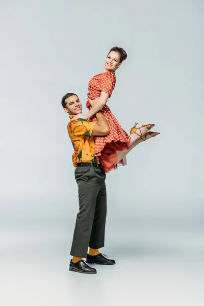 Stylish dancer holding partner while dancing boogie-woogie on grey background — Stock Photo