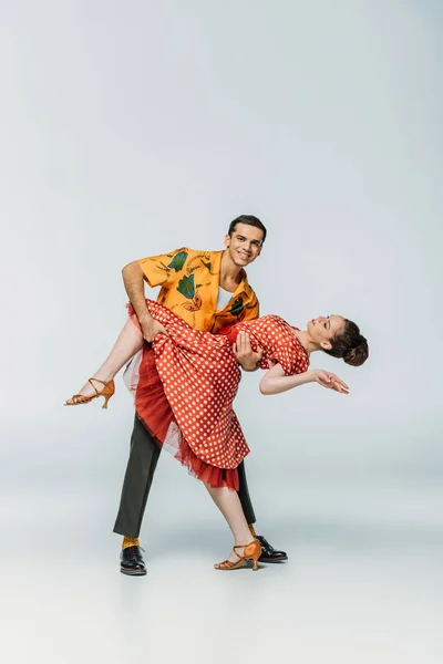 Smiling dancer supporting partner while dancing boogie-woogie on grey background — Stock Photo