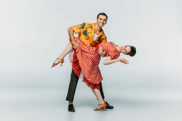 Dançarino elegante parceiro de apoio enquanto dança boogie-woogie no fundo cinza — Fotografia de Stock