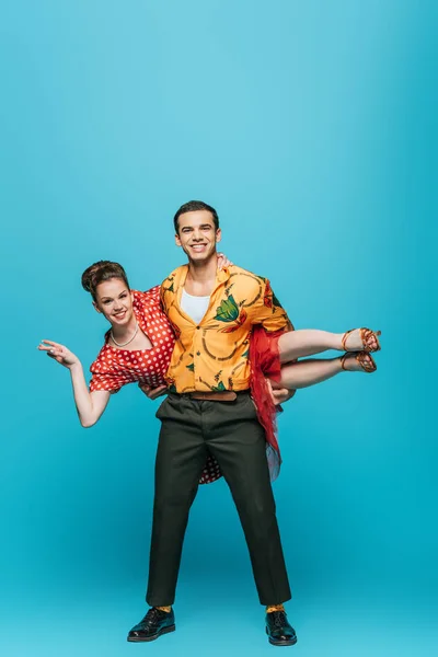 Handsome dancer holding partner while dancing boogie-woogie on blue background — Stock Photo