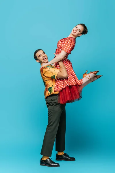 Alegre dançarina segurando parceiro enquanto dança boogie-woogie no fundo azul — Fotografia de Stock