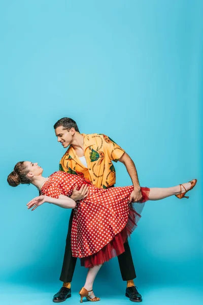 Beau danseur soutien partenaire tout en dansant boogie-woogie sur fond bleu — Photo de stock
