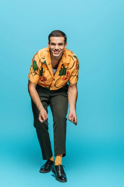 Handsome, cheerful dancer looking at camera while dancing boogie-woogie on blue background — Stock Photo