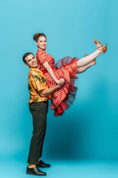 Handsome dancer holding partner while dancing boogie-woogie on blue background — Stock Photo