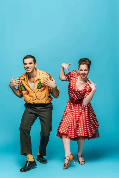Danseurs élégants regardant la caméra tout en dansant boogie-woogie sur fond bleu — Photo de stock