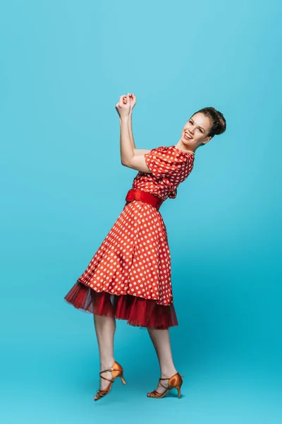 Atractiva, bailarina con estilo mirando a la cámara mientras baila boogie-woogie sobre fondo azul - foto de stock