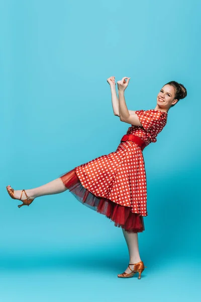 Pretty, stylish dancer looking at camera while dancing boogie-woogie on blue background — Stock Photo