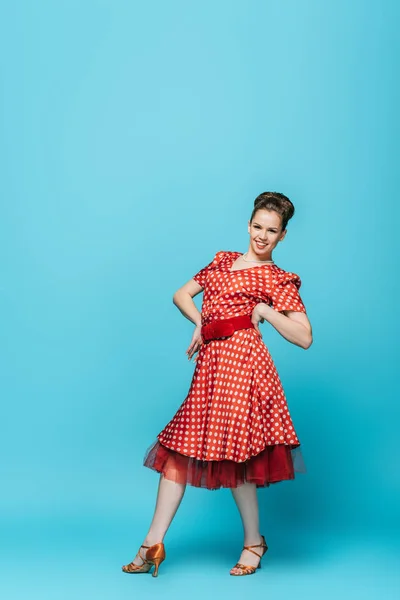 Alegre, dançarina elegante olhando para a câmera enquanto dança boogie-woogie no fundo azul — Fotografia de Stock