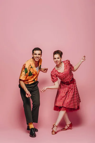 Jeunes danseurs regardant la caméra tout en dansant boogie-woogie sur fond rose — Photo de stock